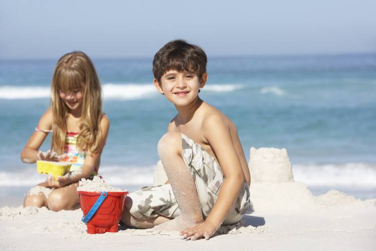 Two kids playing in the sand on the beach